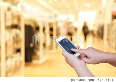 blur smart phone on people walk in shopping mall blur smart phone on people walk in shopping mall 37895104