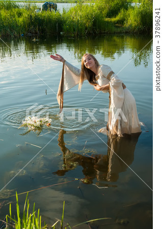 Attractive woman lowers wreath in water Attractive woman lowers wreath in water 37896241