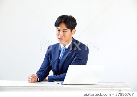 Twenty-something business man sitting and working on a laptop Twenty-something business man sitting and working on a laptop 37896767