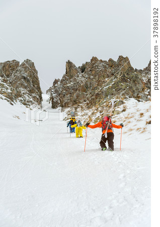 Extreme skiers climb to the top along the couloir 37898192