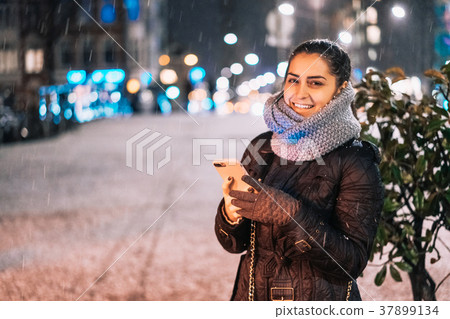 Stylish woman holding phone in city street Stylish woman holding phone in city street 37899134
