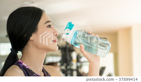 Asian girl in fitness is drinking fresh water Asian girl in fitness is drinking fresh water 37899414