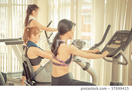 Team of girlfriends working out on machines Team of girlfriends working out on machines 37899415