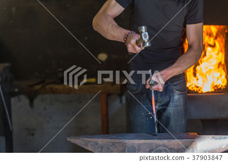 farrier making a traditional horseshoe on a forge 37903847