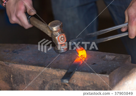 farrier making a traditional horseshoe on a forge 37903849