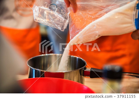 Adding sugar in saucpan close Adding sugar in saucpan close 37911155