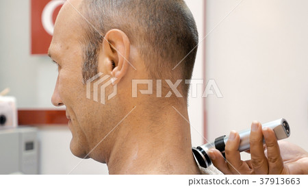 Barber is shaving his client in old fashion manner 37913663