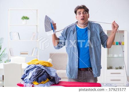 Young man husband doing clothing ironing at home Young man husband doing clothing ironing at home 37925577