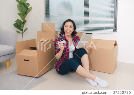 Young woman sitting on the floor holding a tablet 37930750