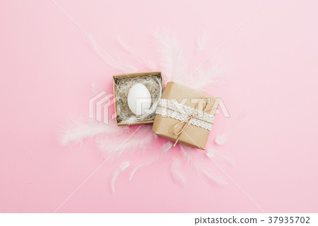 Easter egg in paper box and feather on pastel pink Easter egg in paper box and feather on pastel pink 37935702