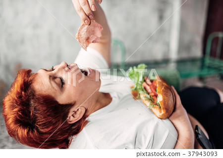 Overweight woman eats sandwich, bulimic, obesity 37943093
