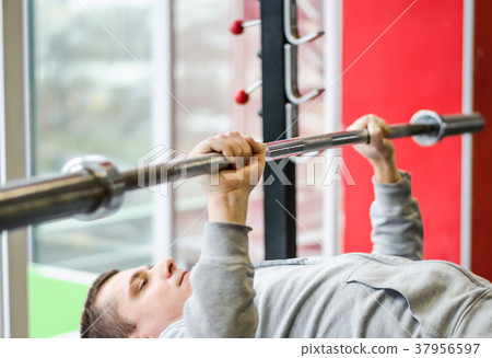 Young male patient doing bench press exercise at Young male patient doing bench press exercise at 37956597