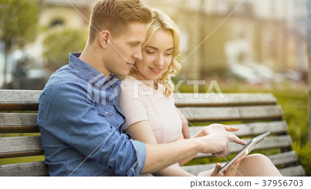 Students in love sitting on bench, using laptop Students in love sitting on bench, using laptop 37956703