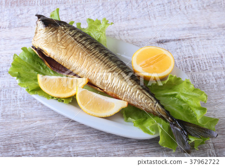 Smoked fish and lemon on green lettuce leaves 37962722