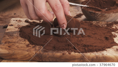 female hands making truffles in cocoa powder on 37964670