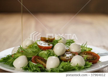 pouring olive oil on caprese salad variation with pouring olive oil on caprese salad variation with 37964812