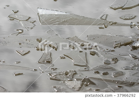 A puddle was broken of frozen ice 37966292