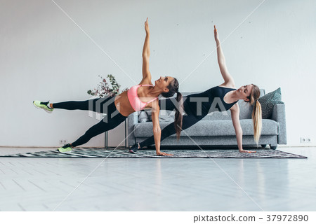 Fit women doing side plank exercise practicing 37972890