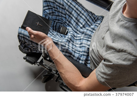 Handicapped man holding bible in arm 37974007