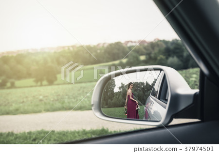 Elegant woman seen in the rearview mirror of car 37974501
