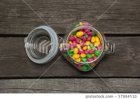 Colorful sweet candy in glass jar on wooden board. Colorful sweet candy in glass jar on wooden board. 37984510
