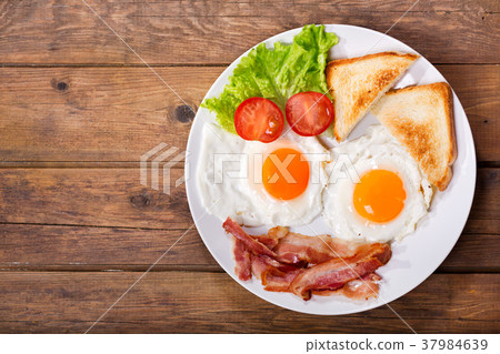 fried eggs with bacon on wooden table, top view fried eggs with bacon on wooden table, top view 37984639