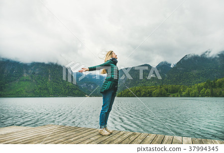 Female traveller standing at mountain lake coast 37994345
