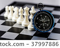 Chess and navigation compass on chessboard in conc 37997886