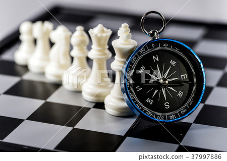 Chess and navigation compass on chessboard in conc 37997886