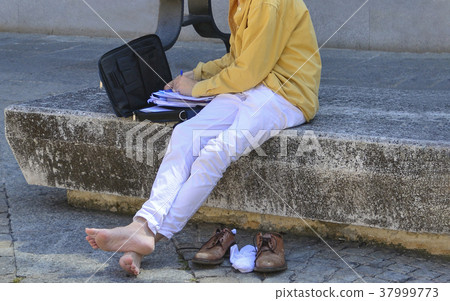 man barefoot sitting on the bench and working man barefoot sitting on the bench and working 37999773