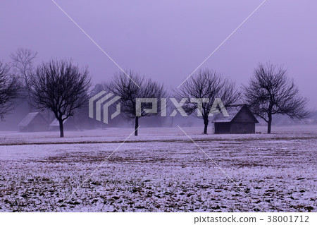 small barn next to the line of trees on rainy day	 38001712
