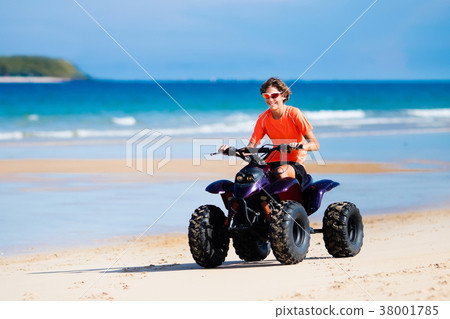 Teenager riding quad bike on beach 38001785