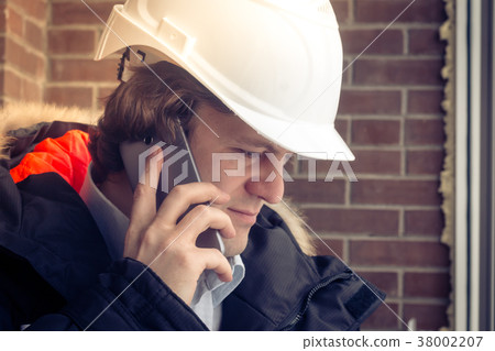 Construction inspector in white helmet talking on Construction inspector in white helmet talking on 38002207