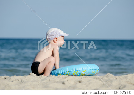 Little blond boy sitting on seashore Little blond boy sitting on seashore 38002538