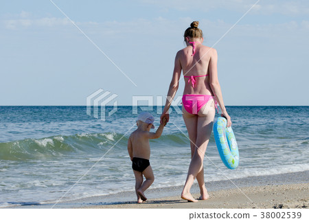 Mom and young son go hand along the line of sea Mom and young son go hand along the line of sea 38002539
