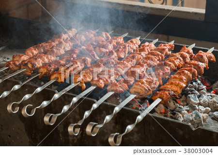 Cooking of a shashlik on a grill on a metal skewer Cooking of a shashlik on a grill on a metal skewer 38003004