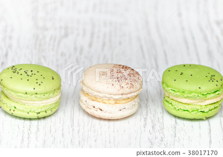 Three macarons on a light wooden table. Close up 38017170