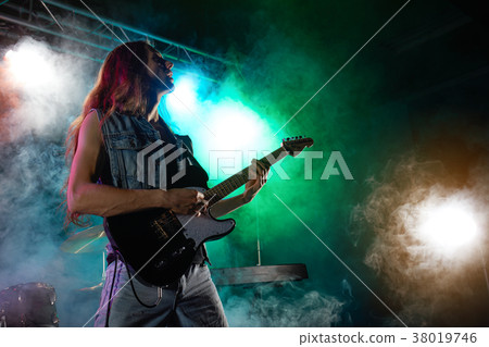 The guitarist performs on stage. 38019746