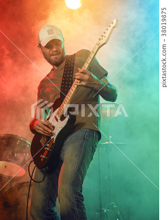 The guitarist performs on stage. 38019875