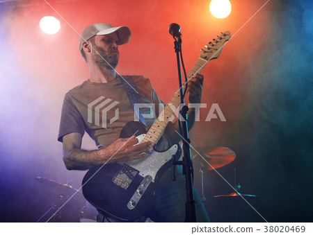 The guitarist performs on stage. 38020469