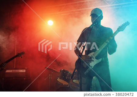 The guitarist performs on stage. 38020472