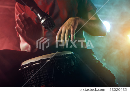 The musician plays the bongo on stage. 38020483