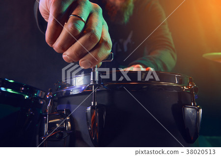 The drummer adjusts the drum set. Scene. Stage light. The drummer adjusts the drum set. Scene. Stage light. 38020513