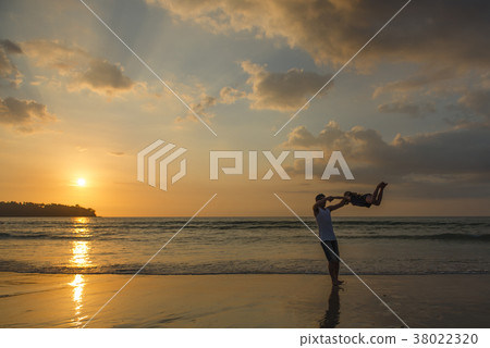 Parents and children playing on sunset beach 38022320