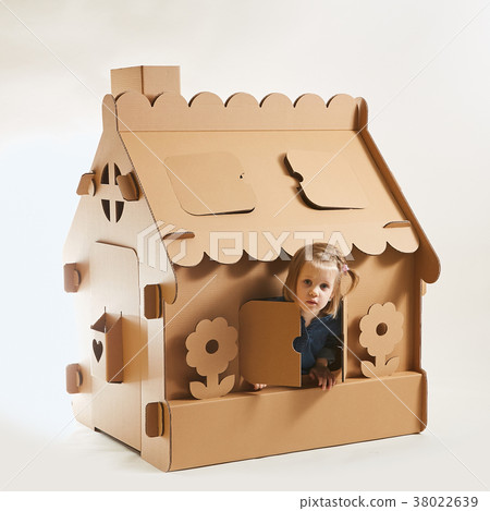 A little girl is playing in a cardboard house. The A little girl is playing in a cardboard house. The 38022639