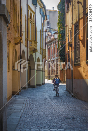 A teen on bicycle is riding along the old streets  38026479