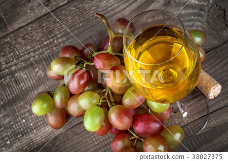 Glass of white wine with a cluster of grapes 38027375