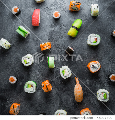 Pattern made of raw sushi rolls on a dark back Pattern made of raw sushi rolls on a dark back 38027490