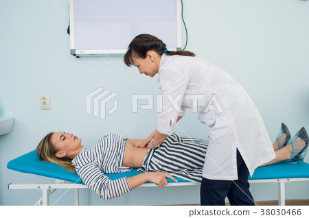 Doctor checking the stomach of one of her patients Doctor checking the stomach of one of her patients 38030466