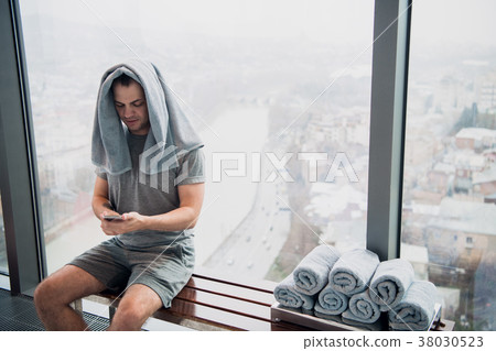 Young, tired man sitting on bench in a gym Young, tired man sitting on bench in a gym 38030523